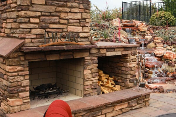 Closeup of an outdoor fireplace and water feature designed and installed by Zebrascapes